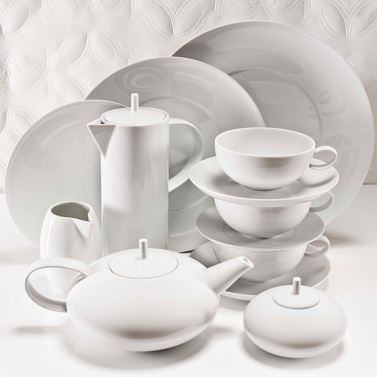 Juego de vajilla blanca apilado, con platos de diferentes tamaños.
