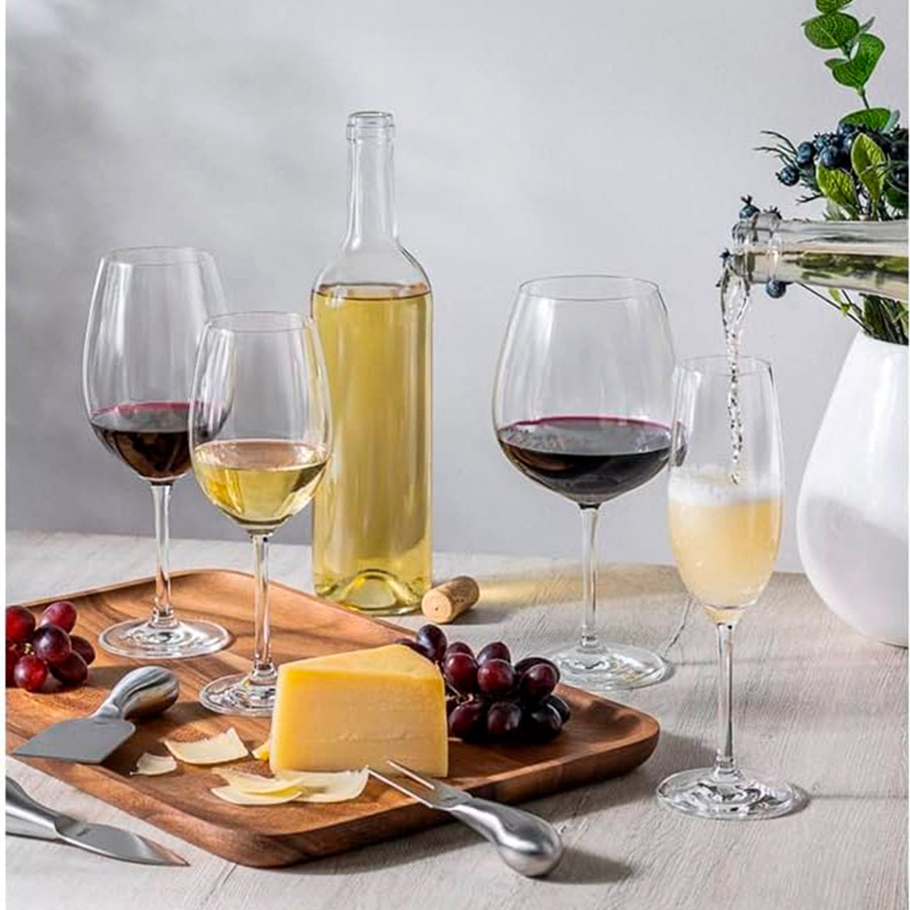 Copas Universal Royal de Stölzle Lausitz llenas de vino blanco y tinto junto una tabla de madera.