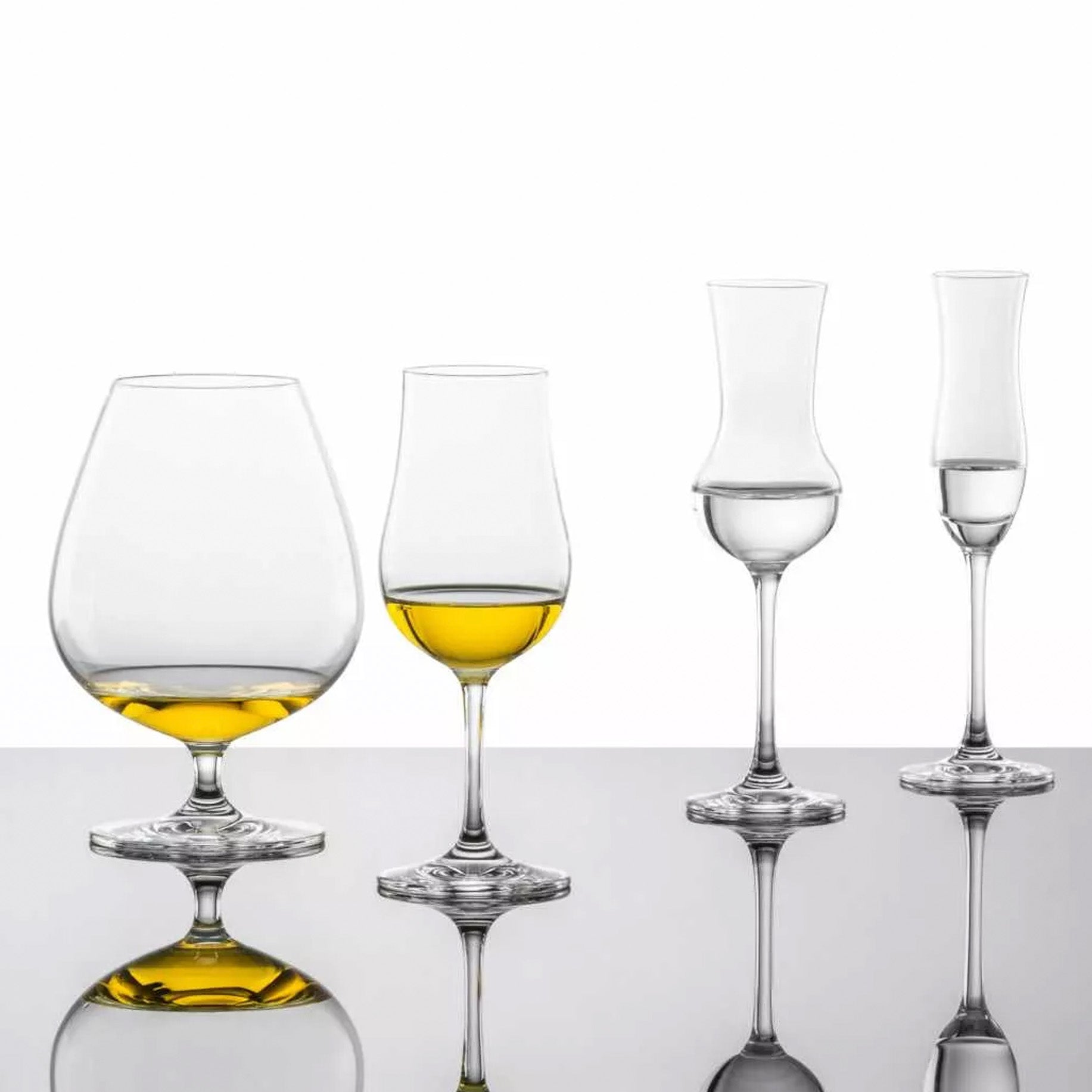 Conjunto de vasos y copas de la colección BAR Special de Zwiesel sobre una barra de bar de vidrio.