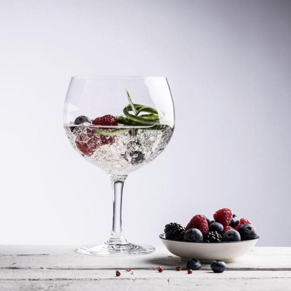 Copa de Gin Tonic clásica con un diseño de globo, sobre una mesa de madera.