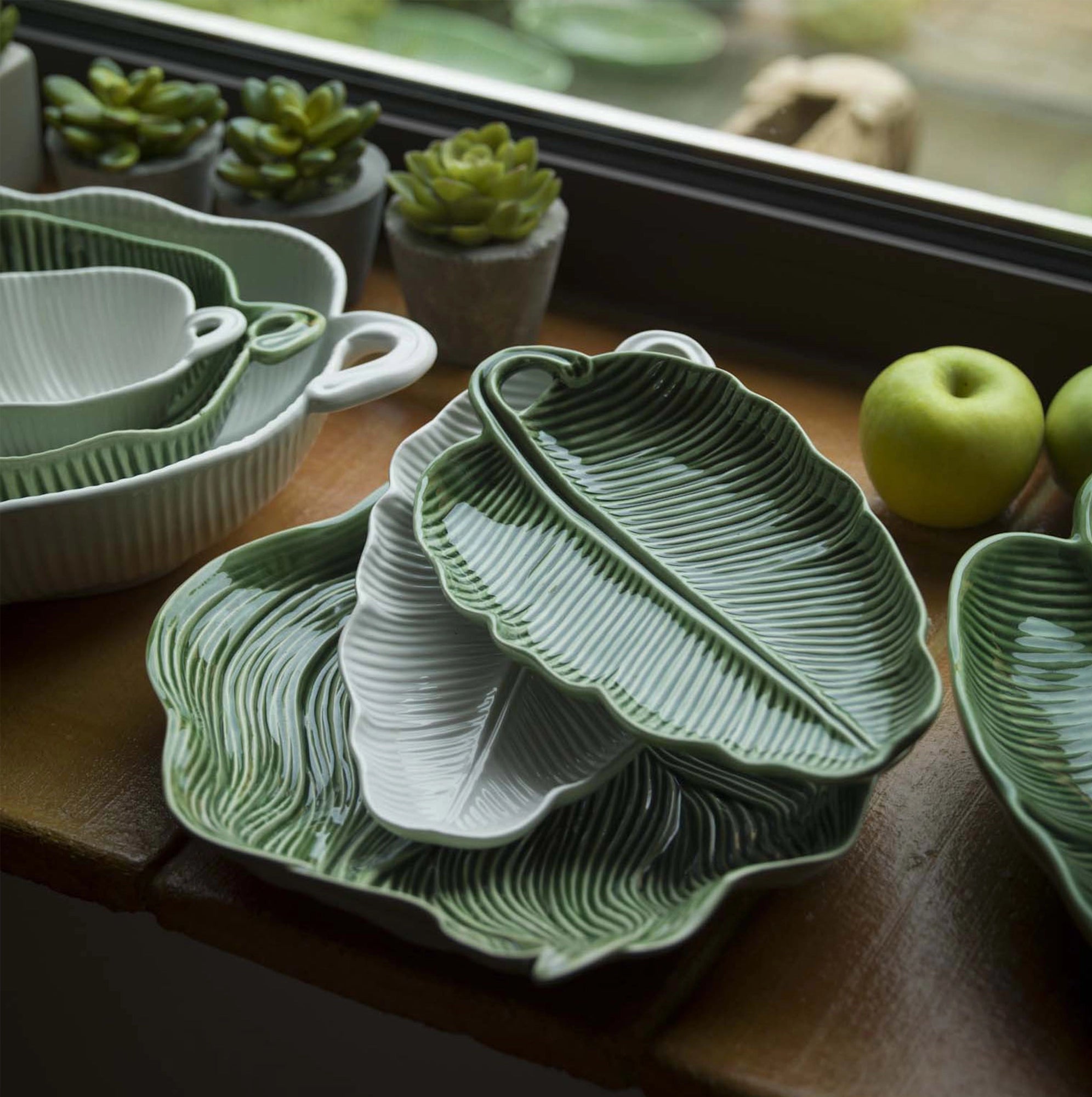 Mesa con varias bandejas de hojas de Bordallo Pinheiro de diferentes tamaños.