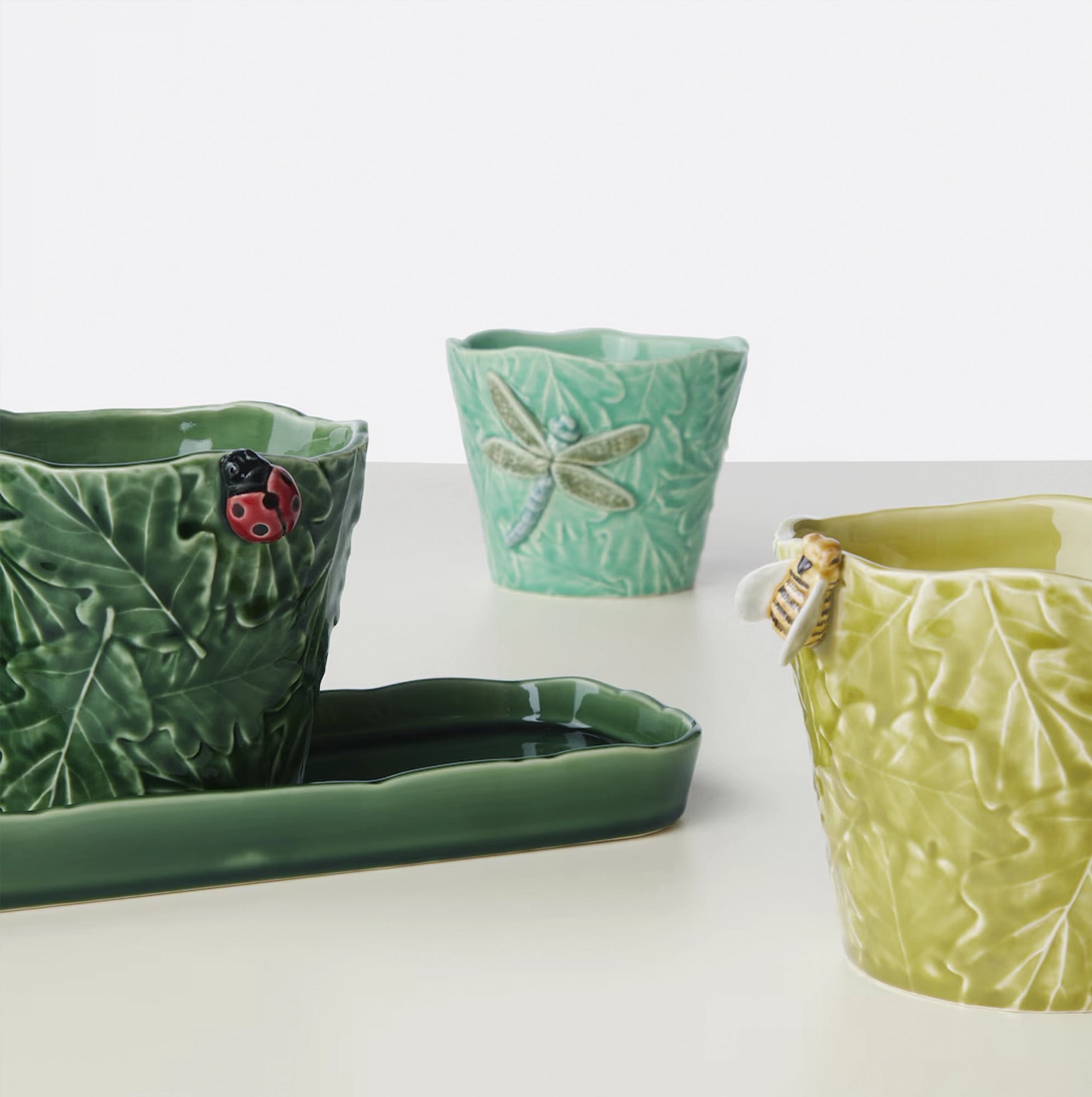 Juego de materas de cerámica de diferentes tamaños, con esculturas en su exterior.