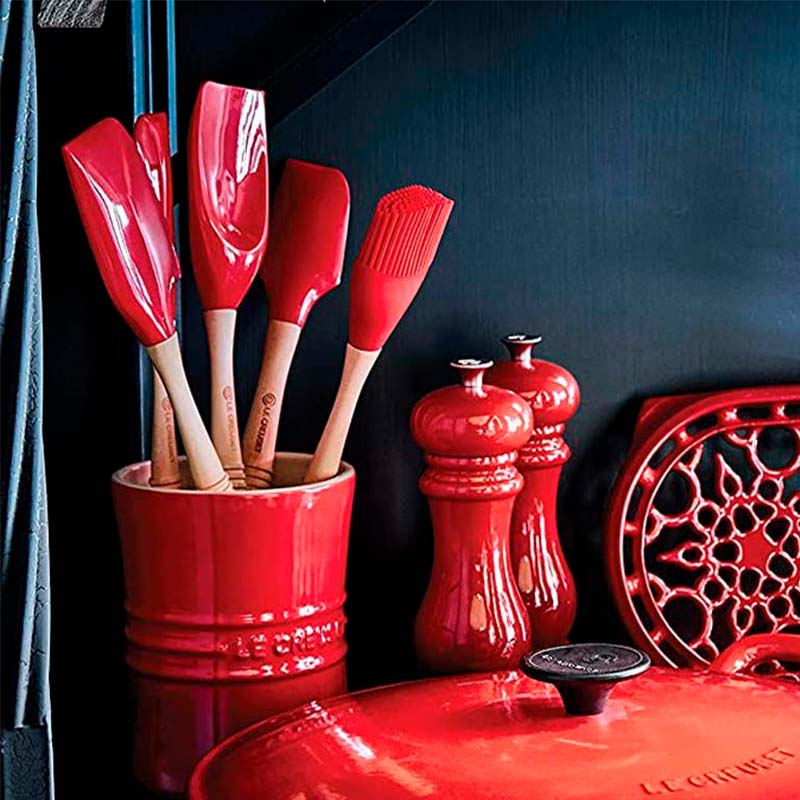 Set de utensilios de cocina de madera y silicona en un recipiente sobre una encimera.