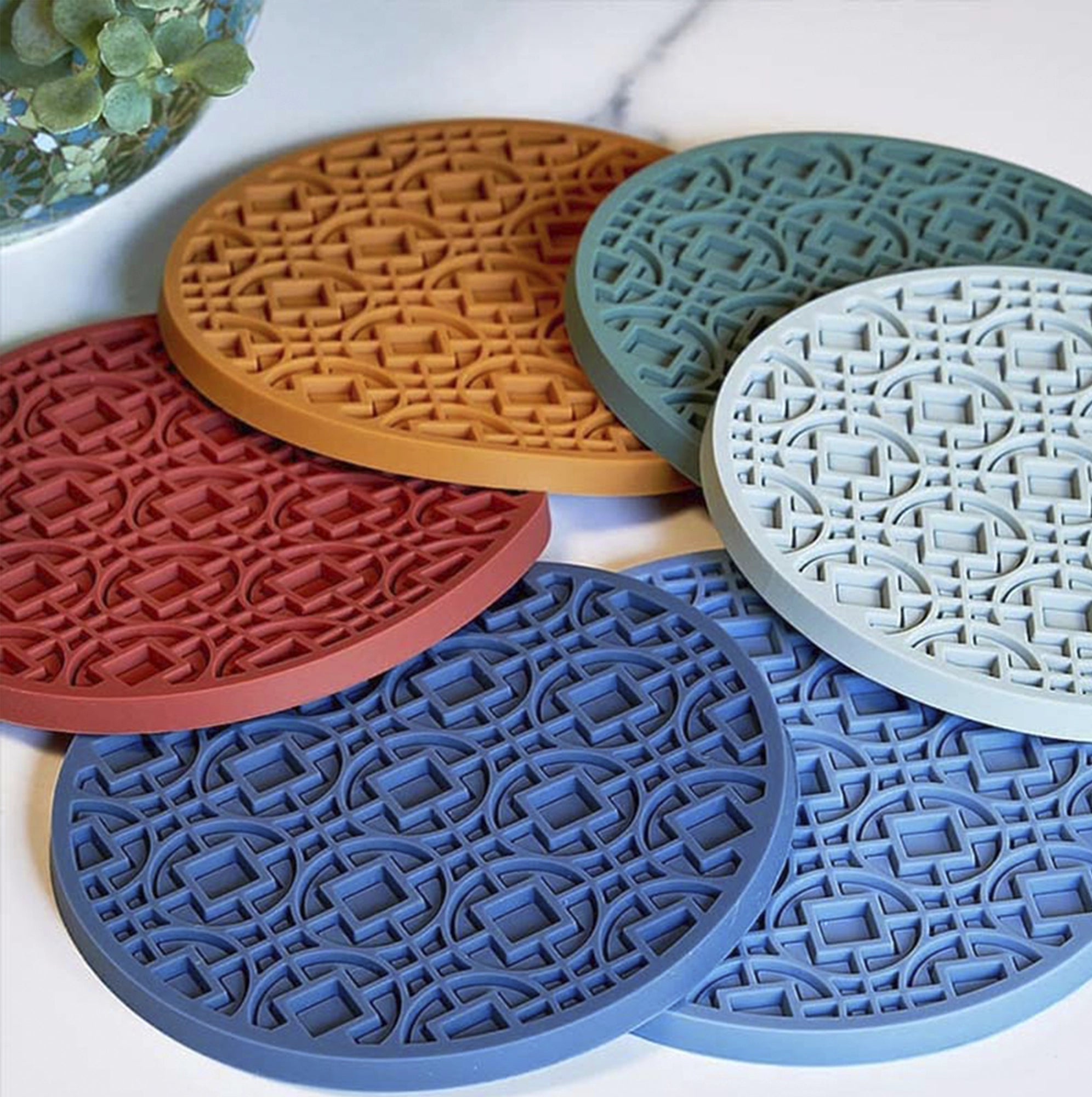 Conjunto de posavasos de silicona de colores vibrantes, apilados en una encimera de cocina.