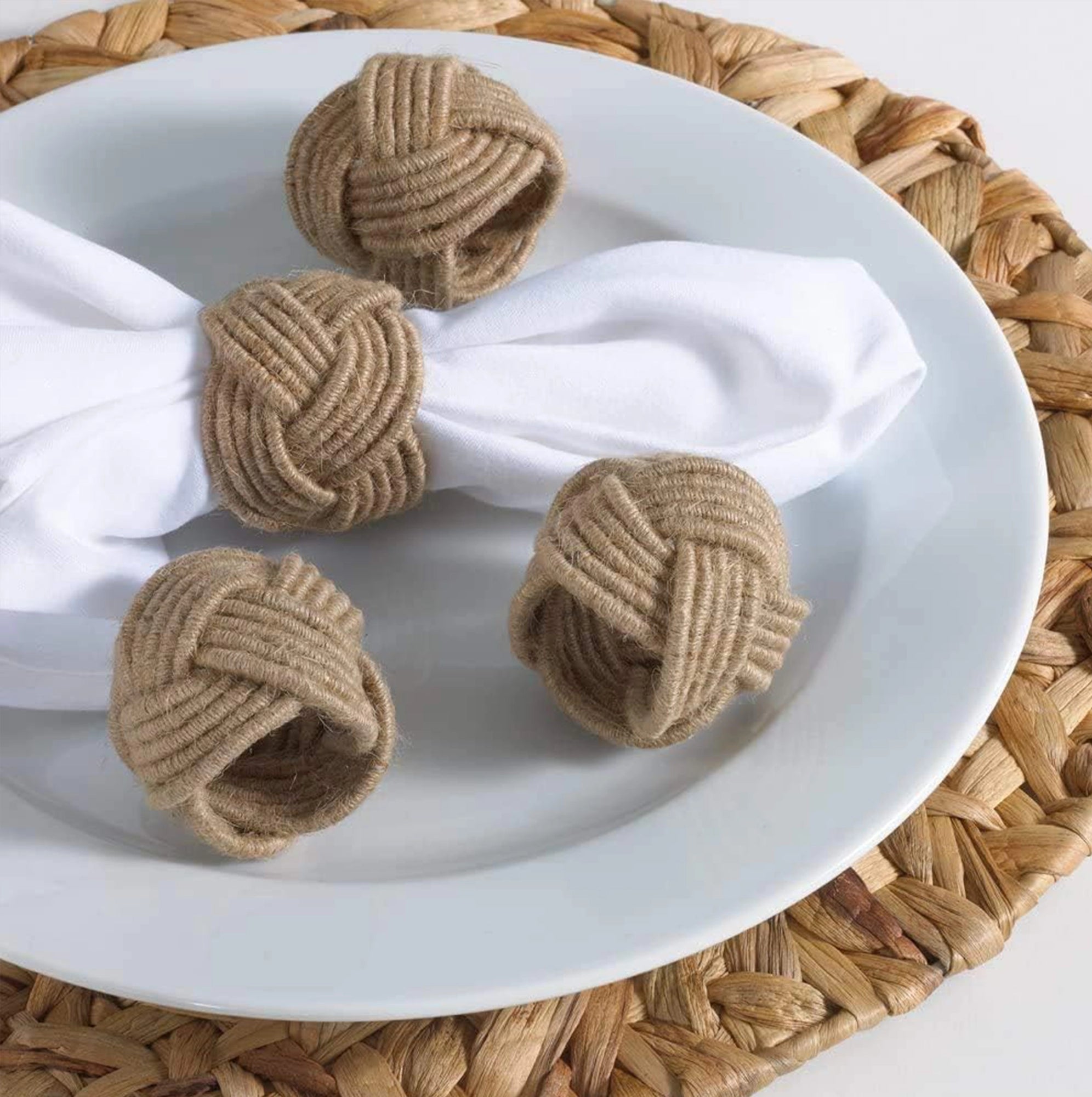 Conjunto de servilleteros de yute con un lazo, con una servilleta de tela de color blanco.