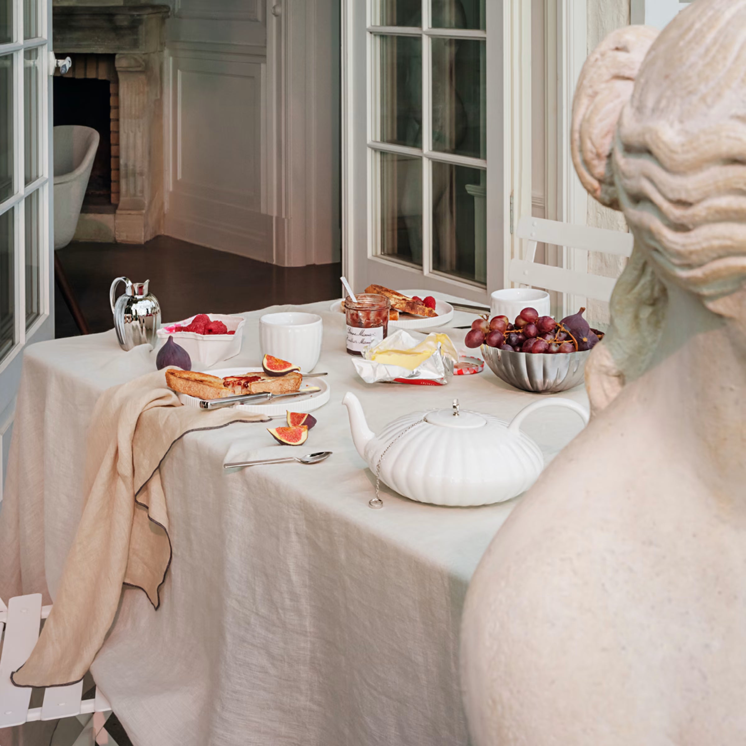 El centro de mesa mediano Bernadotte de Georg Jensen sirviendo uvas frescas sobre una mesa de comedor elegantemente vestida.