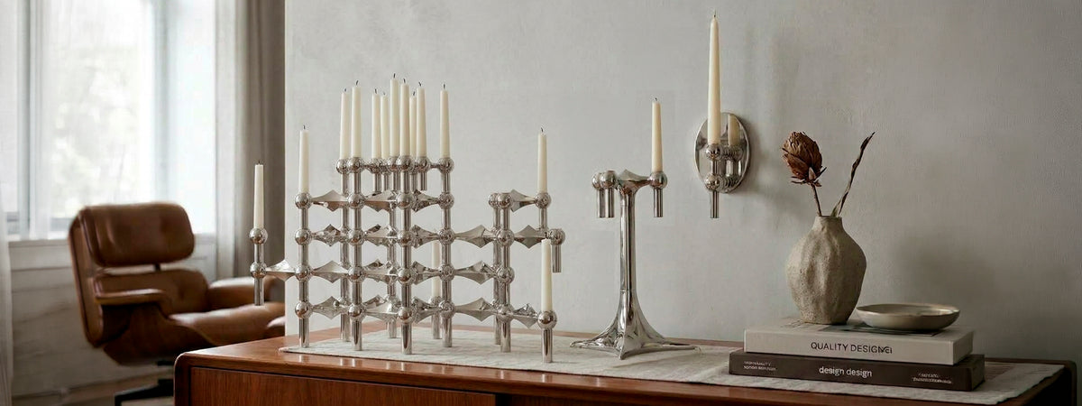 Candelabros modulares cromados Stoff Nagel con velas cónicas sobre aparador de madera en salón de diseño contemporáneo