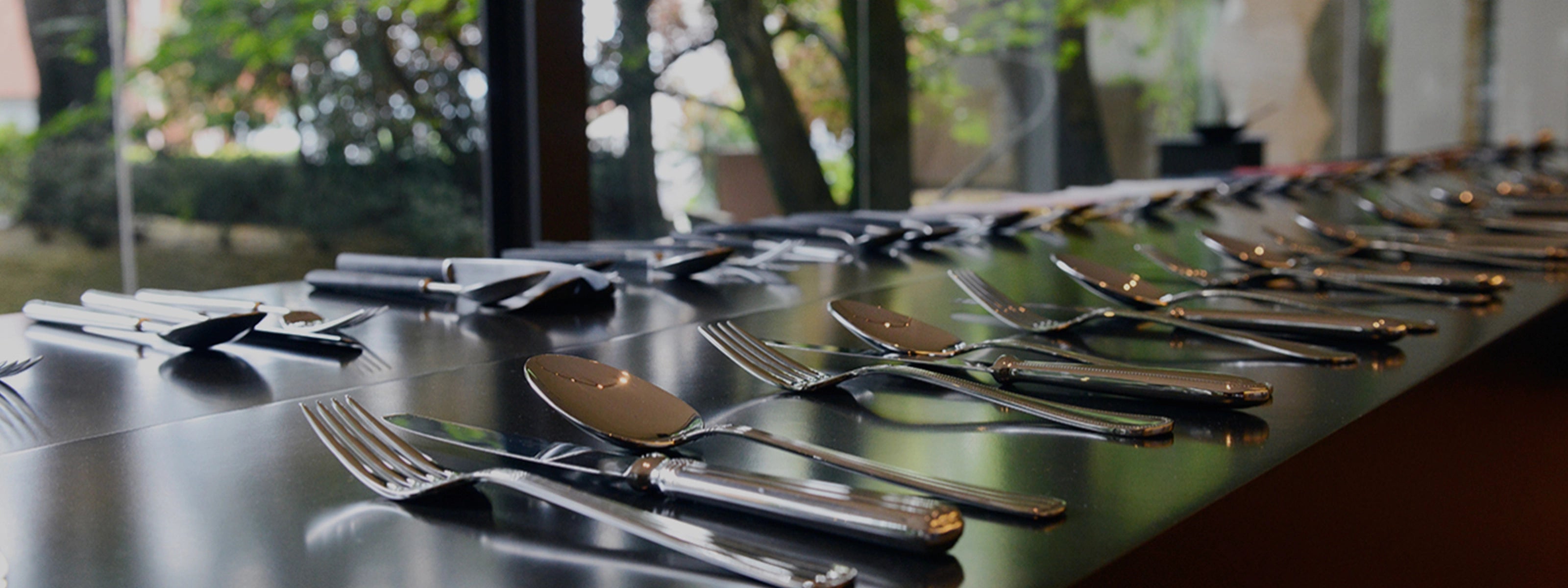 Juegos de cubiertos Cutipol plateados, sobre una mesa oscura.