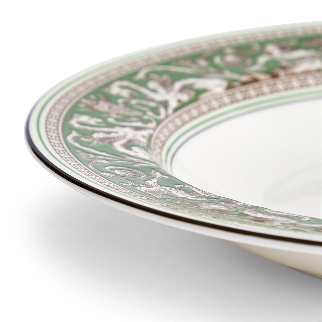 Detalle del borde verde vibrante en el plato hondo Florentine de porcelana.