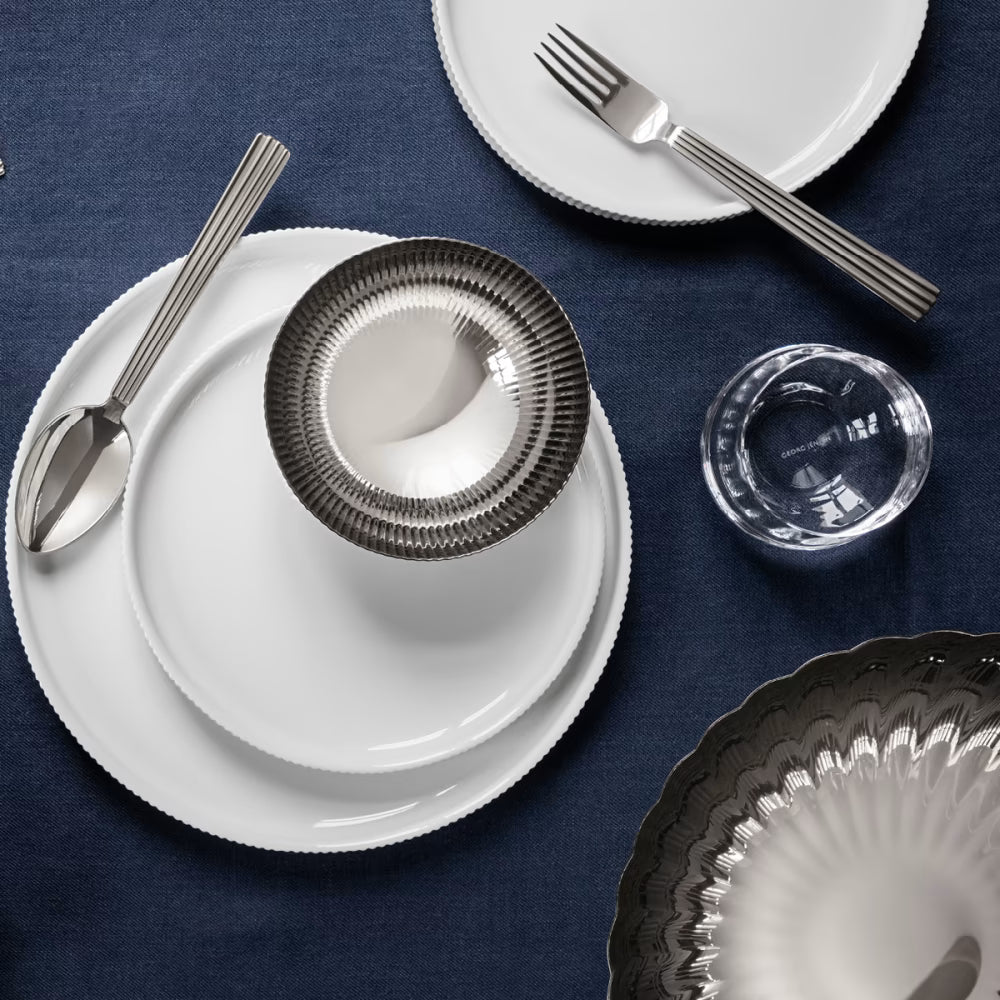 Plato de postre Bernadotte de Georg Jensen, mostrando el diseño estriado y blanco en una mesa.