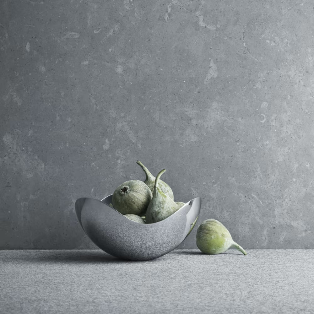 Bowl petit Bloom de Georg Jensen, mostrando el diseño curvo y pulido con snacks en su interior.