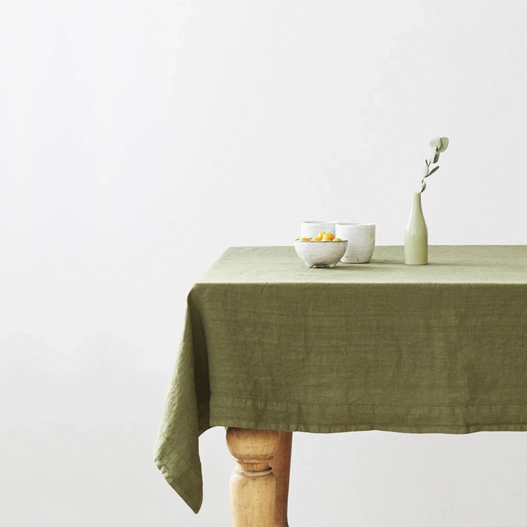 Mantel Martini Olive desplegado sobre una mesa con vajilla rústica