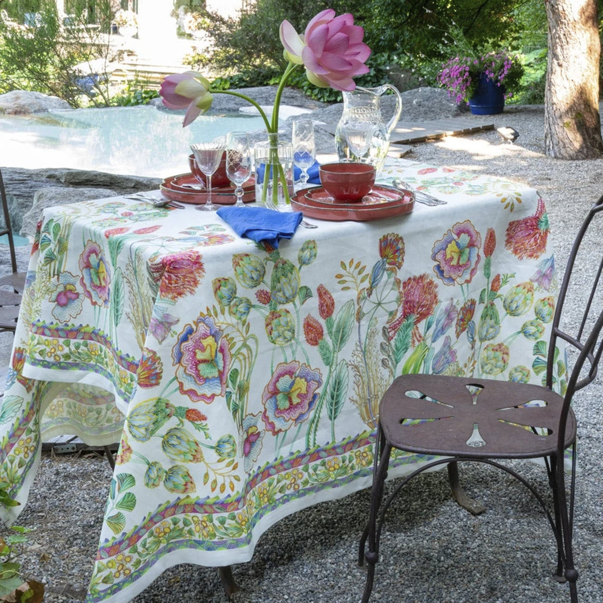 Mantel de lino Artigemme de Tessitura Toscana Telerie montado en una mesa de comedor elegante con vajilla de porcelana y cristalería fina.