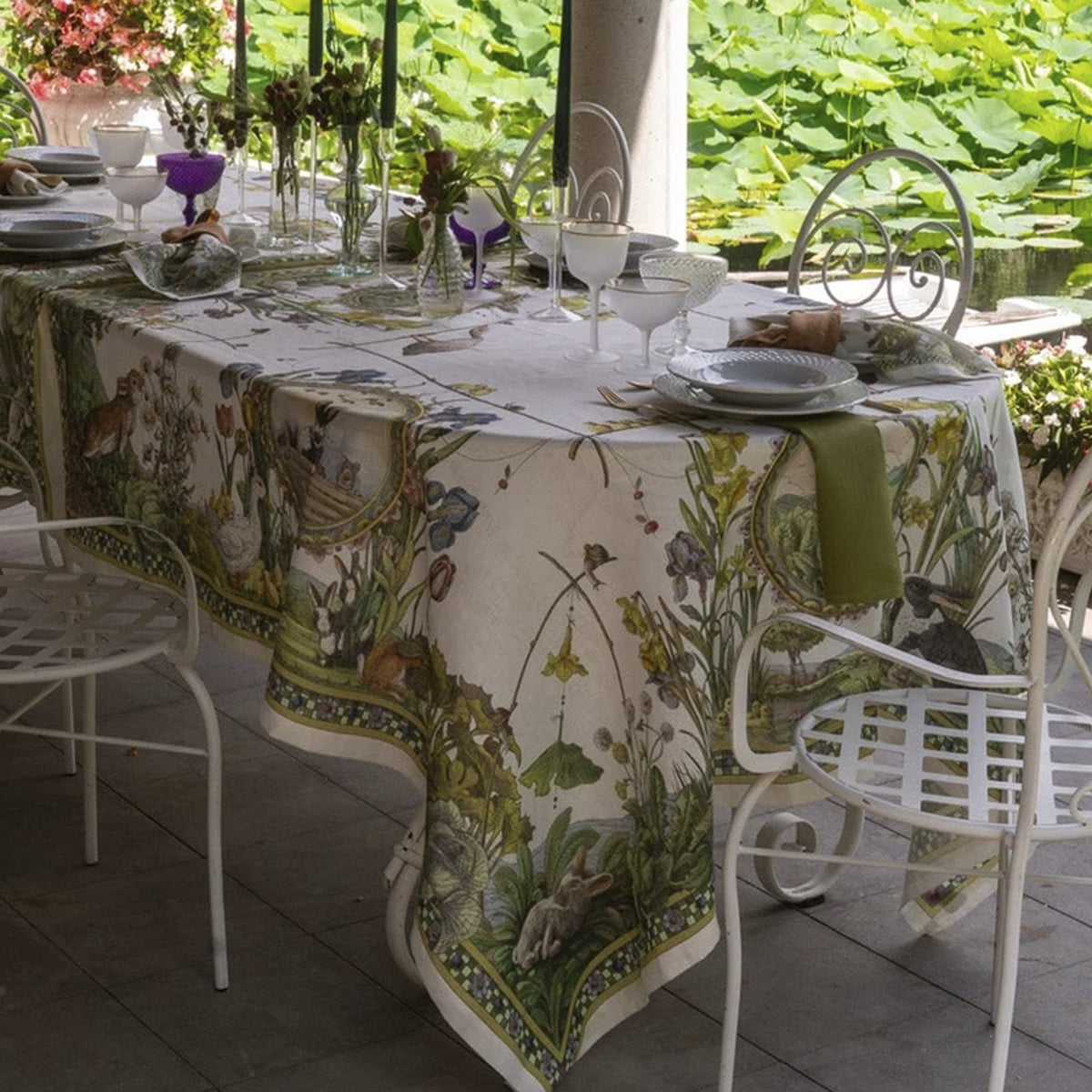 Mantel de lino Bunny Garden de Tessitura Toscana Telerie vistiendo una mesa de brunch campestre con vajilla de porcelana y cristalería fina.