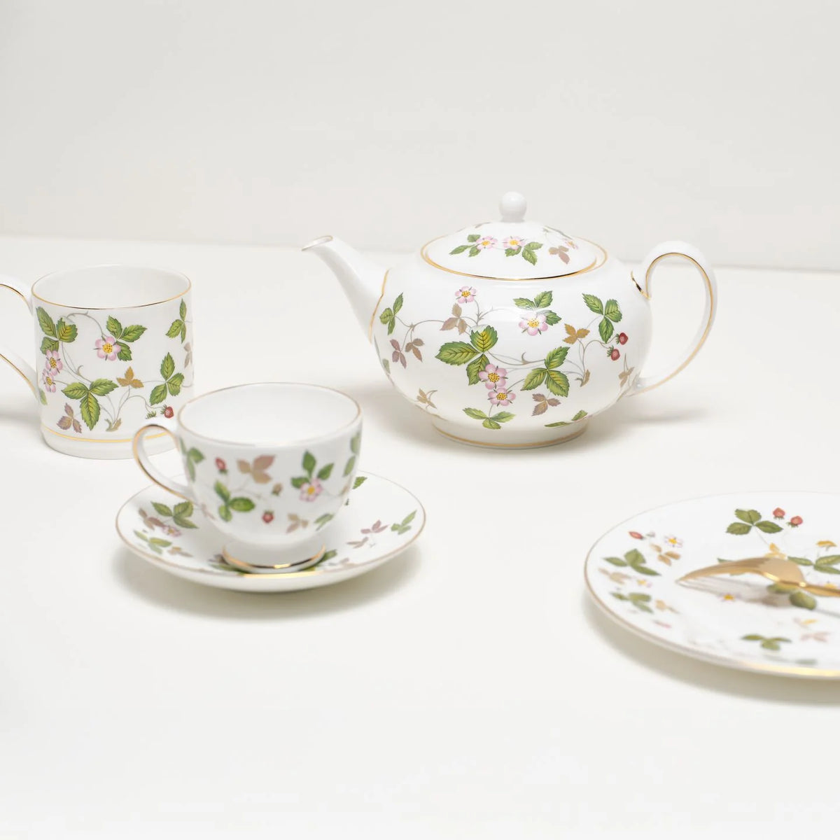 Taza de té Peony Wild Strawberry de Wedgwood servida con té negro humeante sobre un mantel de lino en una mesa de té clásica.