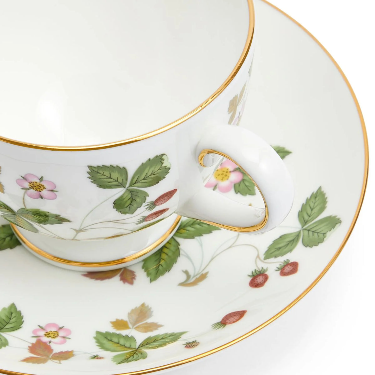 Detalle de la boca ancha acampanada, las fresas silvestres pintadas y el ribete en oro de 22k de la taza de té Peony Wild Strawberry de Wedgwood.
