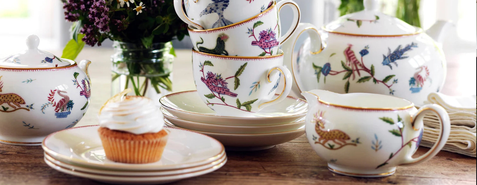 Mesa con la vajilla completa de la colección Mythical Creatures, mostrando diferentes ilustraciones en cada pieza.