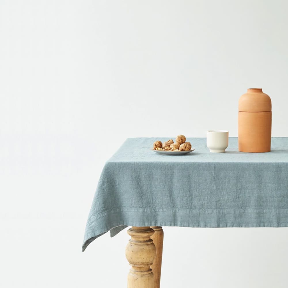 Detalle del mantel de lino Blue Fog Linen Tales sobre mesa de madera