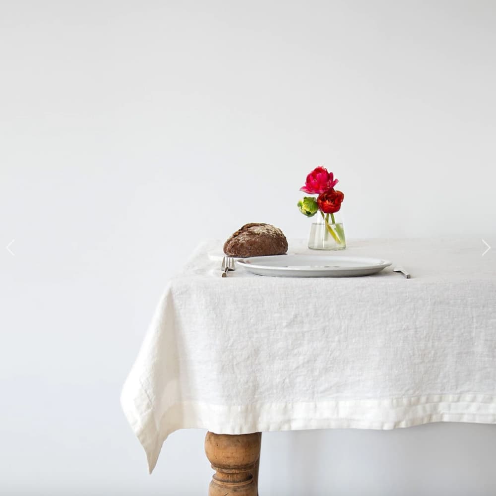 Detalle del mantel de lino White Linen Tales sobre mesa de madera