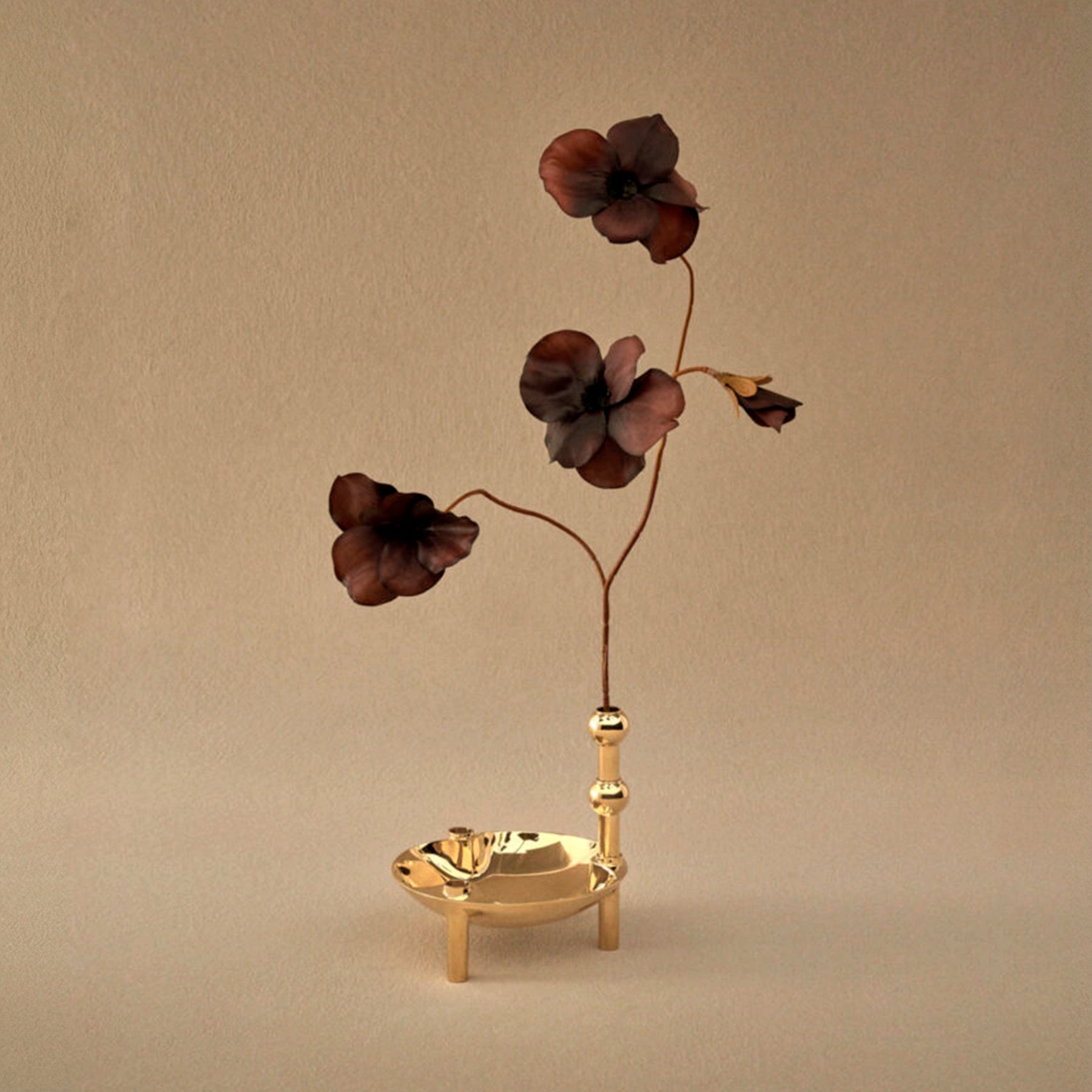 Florero STOFF Nagel Latón integrado en una escultura modular, sosteniendo flores secas y contrastando con el fondo arena.