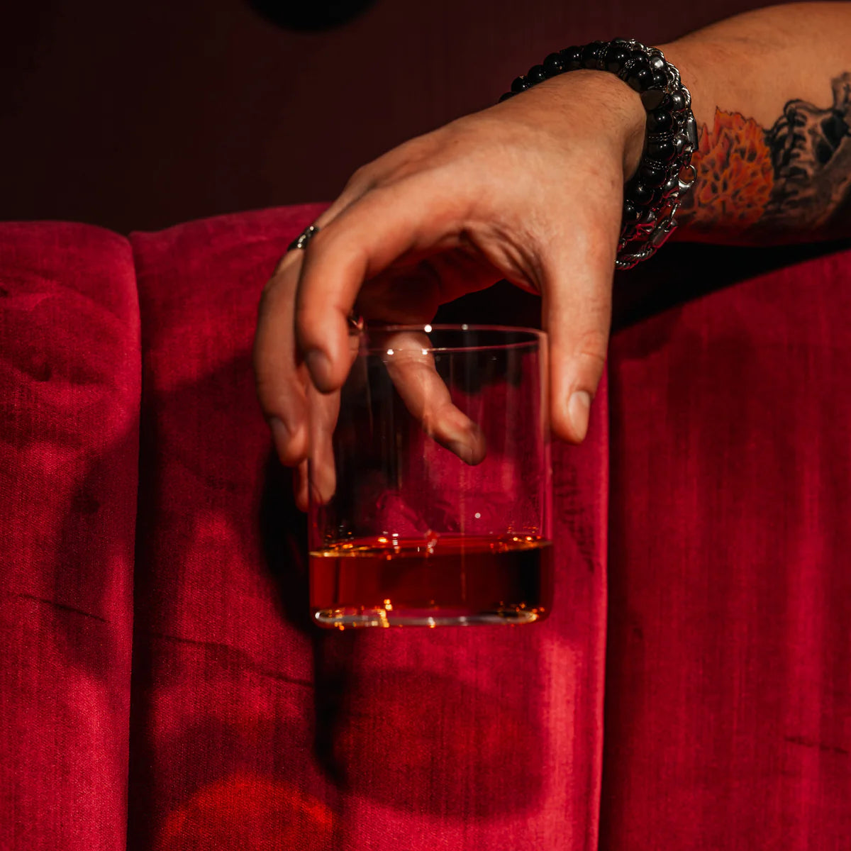 Vaso Whisky Kyoto de Stolzle Lausitz lleno de whisky, listo para degustar, con un fondo de bar acogedor.