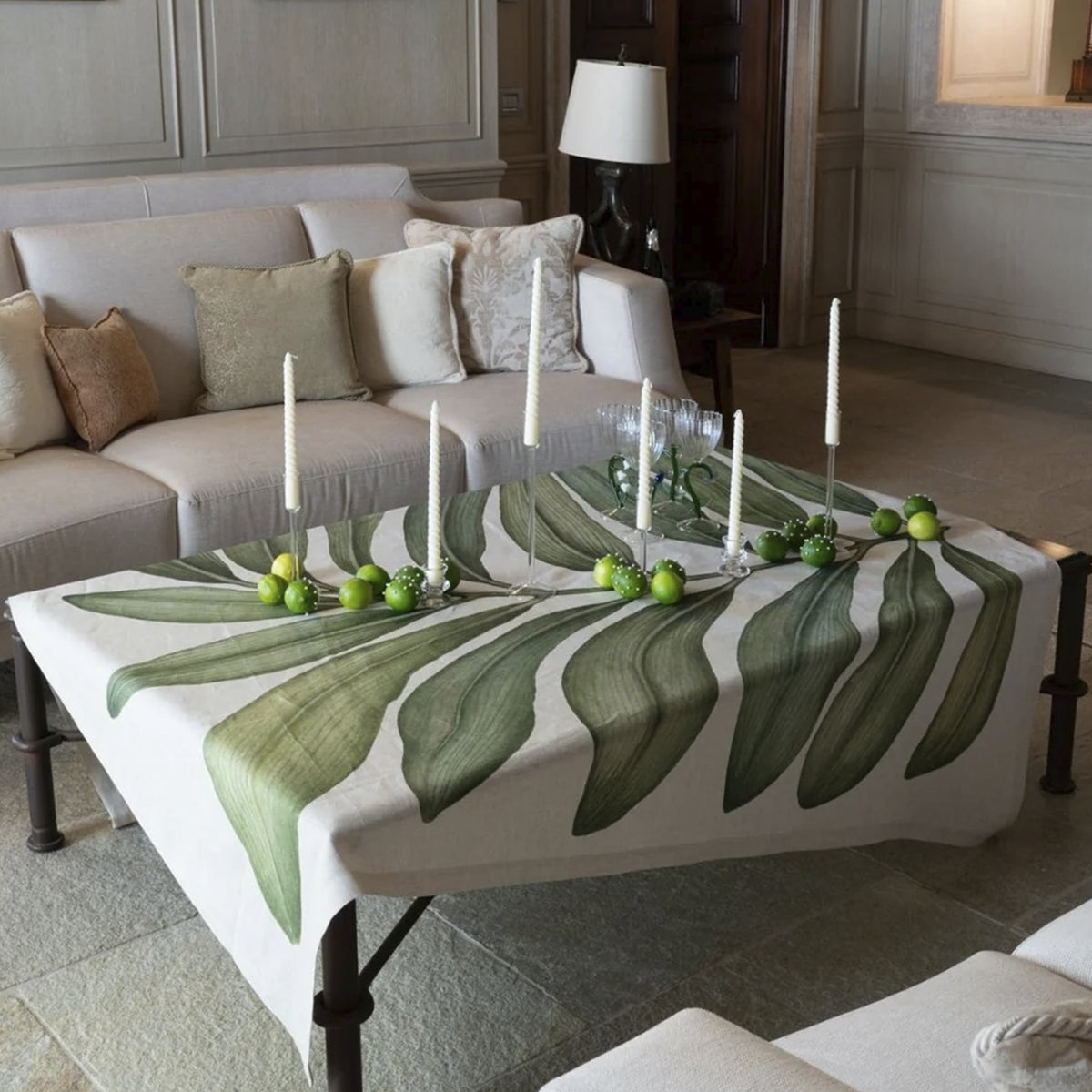 Mantel de lino Tamarindo de Tessitura Toscana Telerie vistiendo una mesa de comedor de verano con candelabros elegantes.