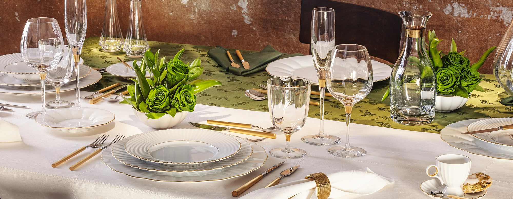 Vista panorámica de la Colección Vista Alegre 200 Años, mostrando vajilla de porcelana y copas de cristal con bordes dorados.