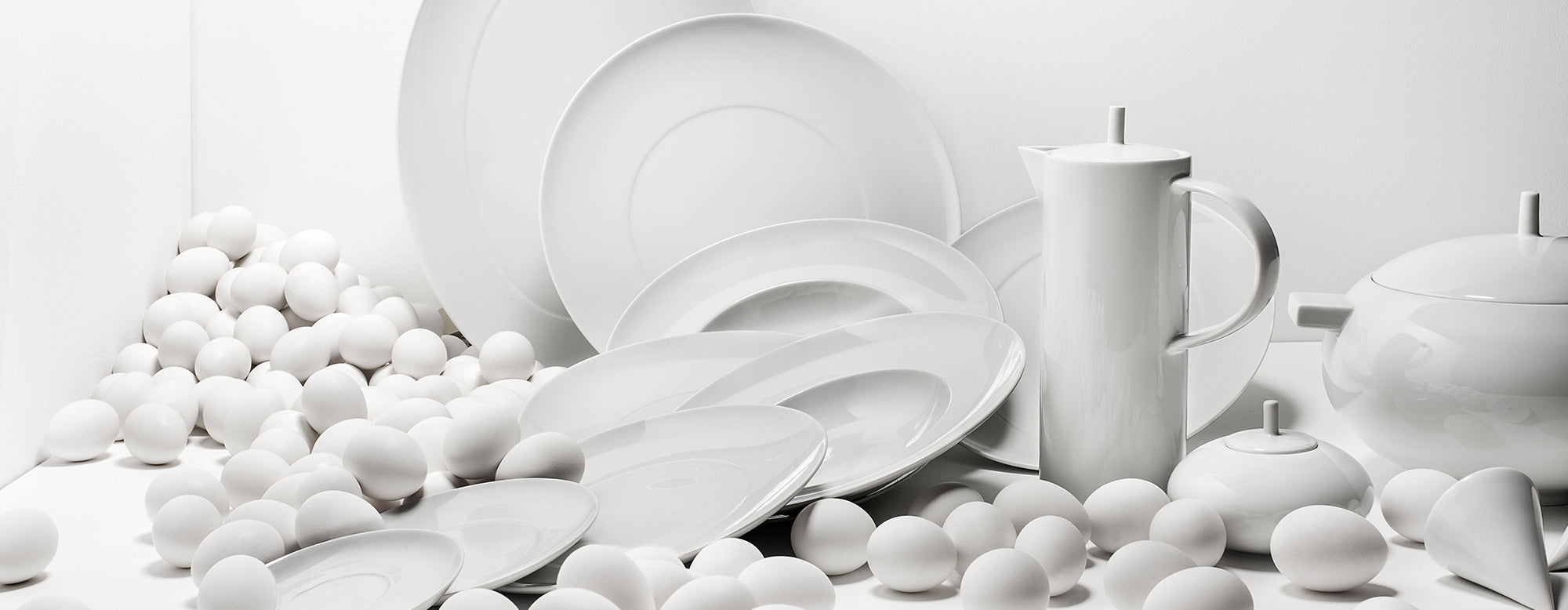 Mesa de comedor con la vajilla de la colección Domo White de Vista Alegre, destacando su diseño minimalista.