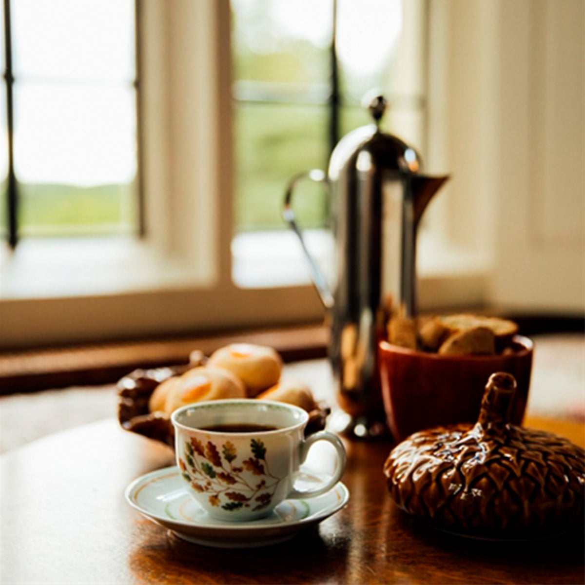 Taza de té y plato Gudrun de Vista Alegre con infusión humeante sobre una mesa de madera cálida en un servicio de té refinado.
