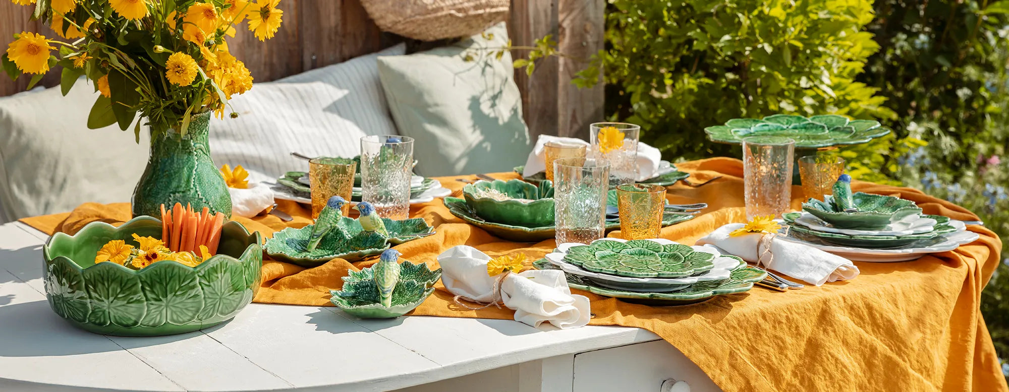 Una mesa decorada con la vajilla de la colección Geranio de Bordallo Pinheiro, en un ambiente rústico y alegre.