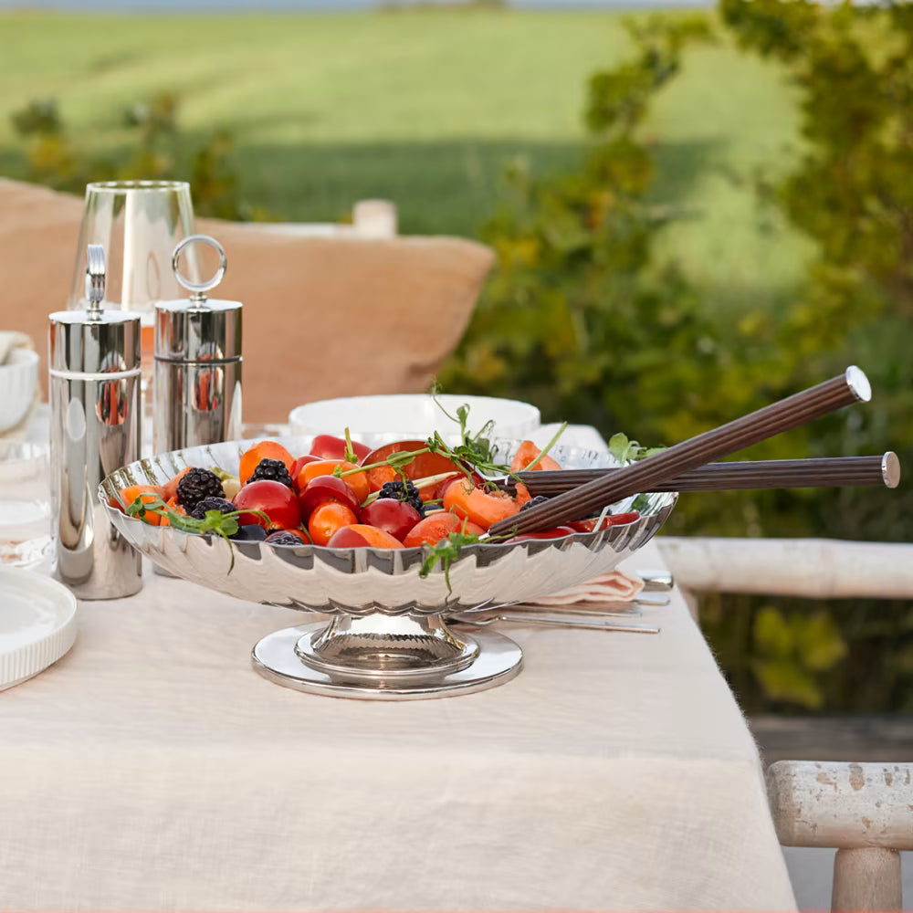 El plato sobre pedestal Bernadotte de Georg Jensen sirviendo como elegante frutero central sobre una mesa de comedor de diseño escandinavo.