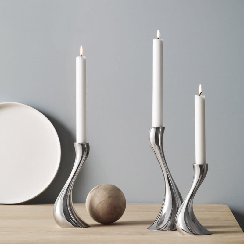 Candelabros Cobra, destacando el brillo del acero inoxidable pulido a espejo y la forma orgánica sobre una mesa contemporanea.