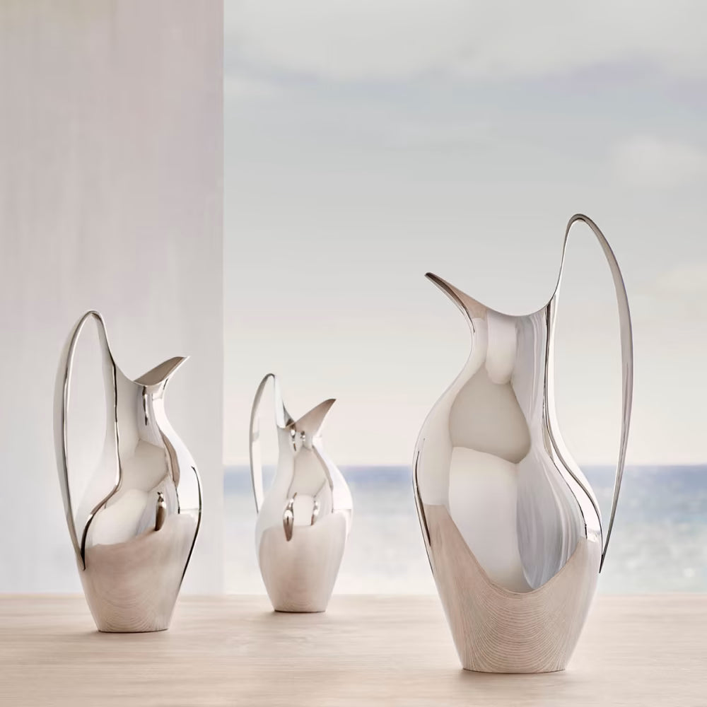 Jarra Koppel 0.75 L de Georg Jensen, mostrando el diseño curvo y pulido con agua en su interior.