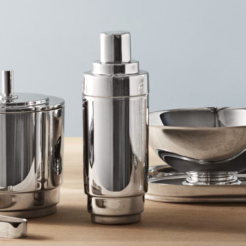 Coctelera Manhattan de Georg Jensen, mostrando el diseño estriado y pulido sobre una mesa de bar.