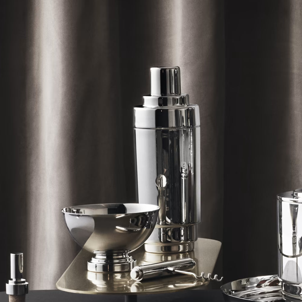 Coctelera Manhattan de Georg Jensen, mostrando el diseño estriado y pulido sobre una mesa de bar.