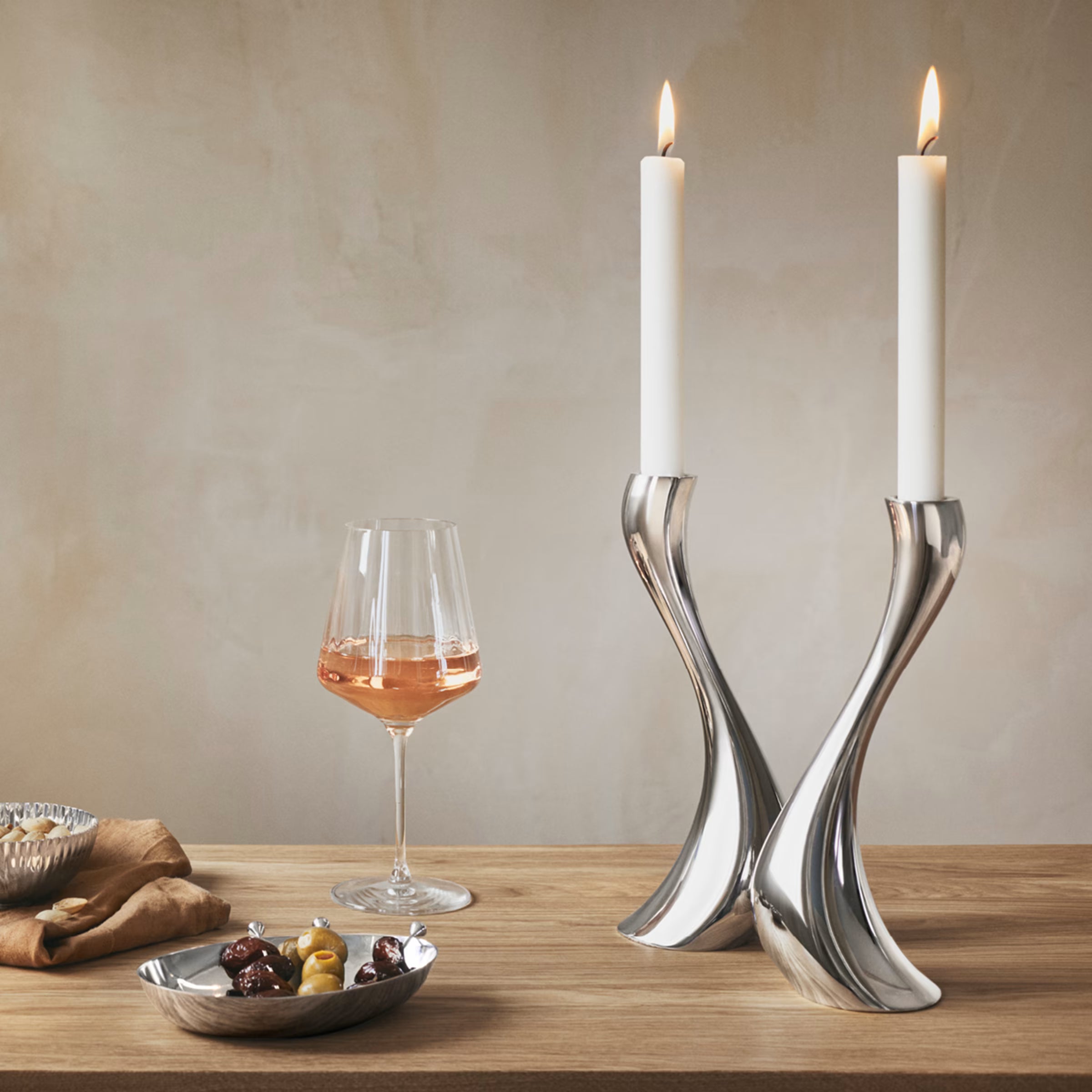 l set de palillos Sky de Georg Jensen dispuesto de manera elegante junto a una copa de vino en una barra de bar contemporánea.
