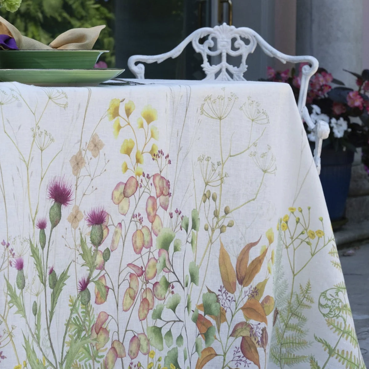 Primer plano de la trama del tejido de lino natural y los detalles en alta definición de la flora exótica del mantel Selvatica de Tessitura Toscana Telerie.