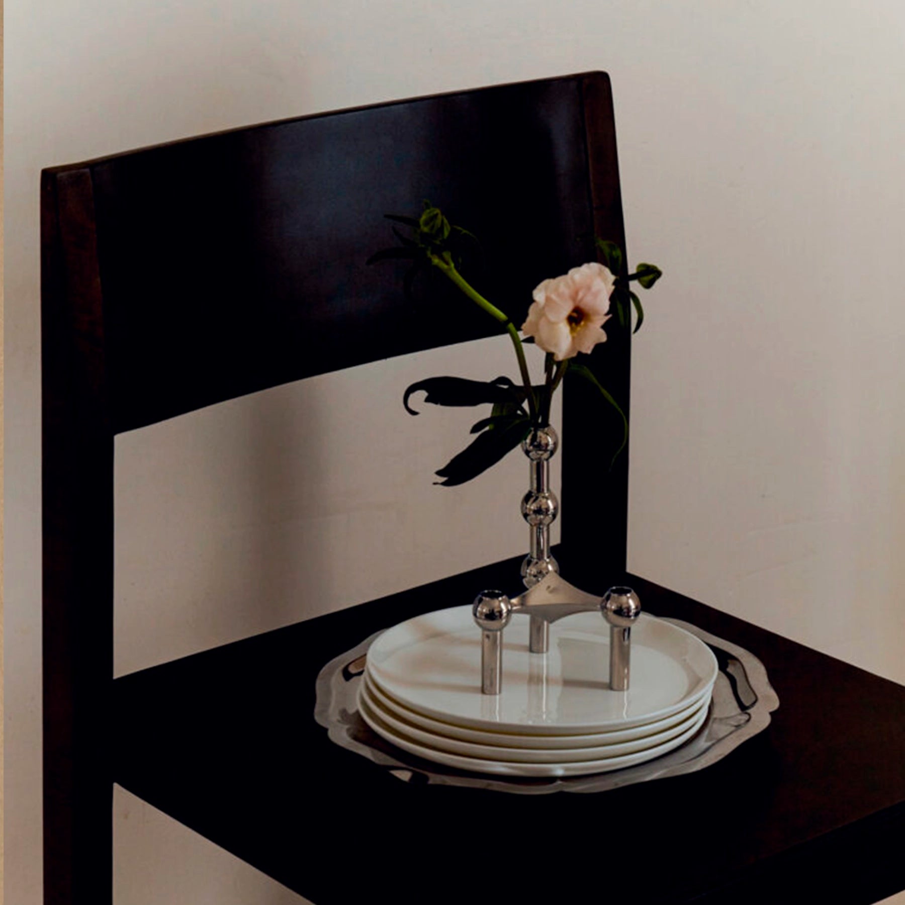 Florero STOFF Nagel Cromo integrado en una escultura de candelabros, sosteniendo una flor minimalista.