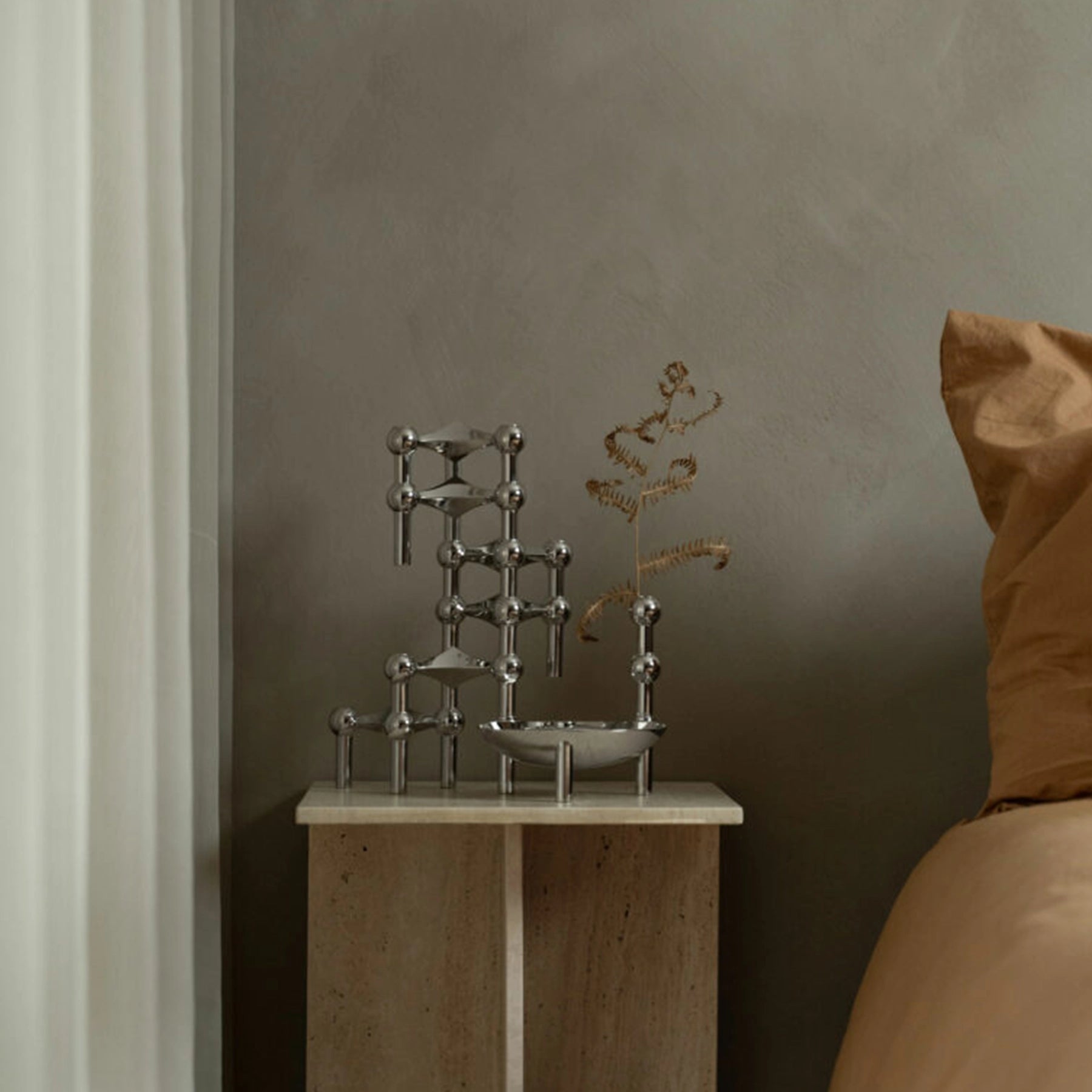 Set de candelabros cromados Nagel STOFF con velas cónicas encendidas.